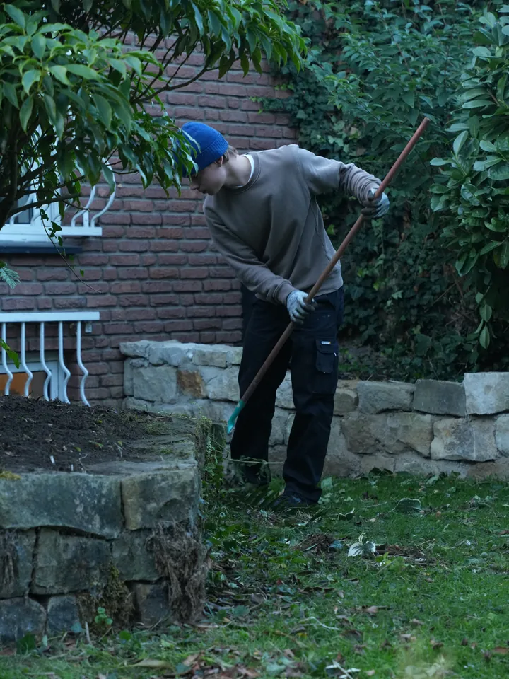 Phillipp Götz lockert mit der Hacke die Erde an einer Mauer